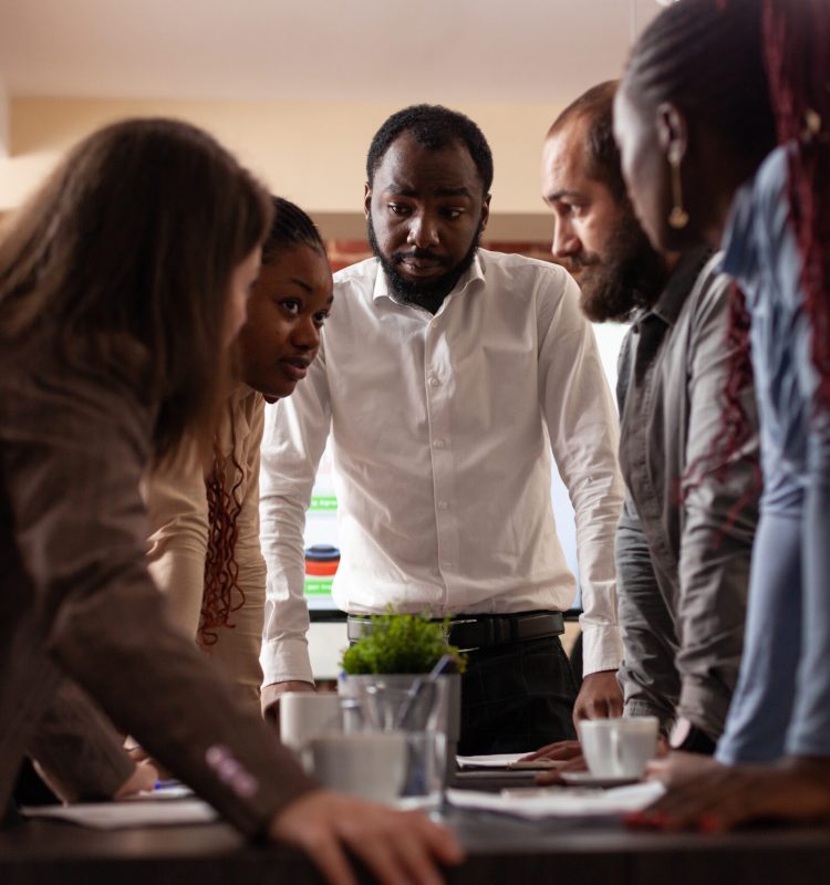 Multi-ethnic entrepreneurs stand up analyzing financial graph brainstorming ideas for partnership project working at company presentation in startup office. Executives managers having business meeting